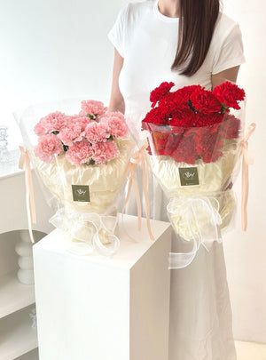 A girl in a white top holds pink and red carnation bouquets, celebrating Mother's Day 2026.