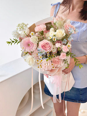 Person holding a bouquet of pink and white flowers against a white background