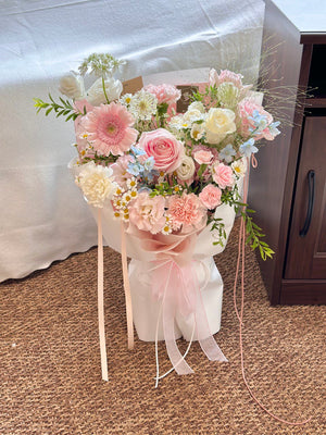 Bouquet of flowers with pink and white ribbons on a carpeted floor.