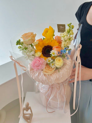 1. A happy graduate woman holds a sunflower bouquet in a clear bag, celebrating her achievement with a gift from a friend.
2. A joyful woman in graduation attire holds a sunflower bouquet in a clear bag, expressing happiness for her friend's gift.
3. A smiling graduate holds a clear bag containing a sunflower bouquet, celebrating her graduation with a thoughtful gift from a friend.