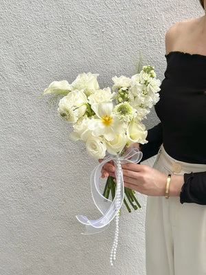 A woman in a wedding dress holds a bouquet of white Calla Lilies, enhancing the beauty of her ROM wedding celebration.