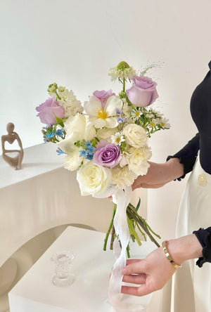A bride with a bouquet of white and Purple flowers, showcasing purple ROM flowers and tulips, celebrates her wedding.