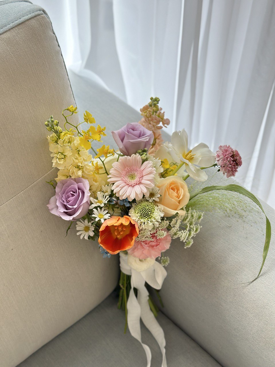 A bride joyfully holds a colorful bouquet of ROM flowers, adding beauty to her wedding day and the surrounding environment.