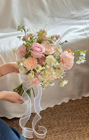 Elegant hand-tied wedding bouquet with romantic blush blooms and wispy greenery.