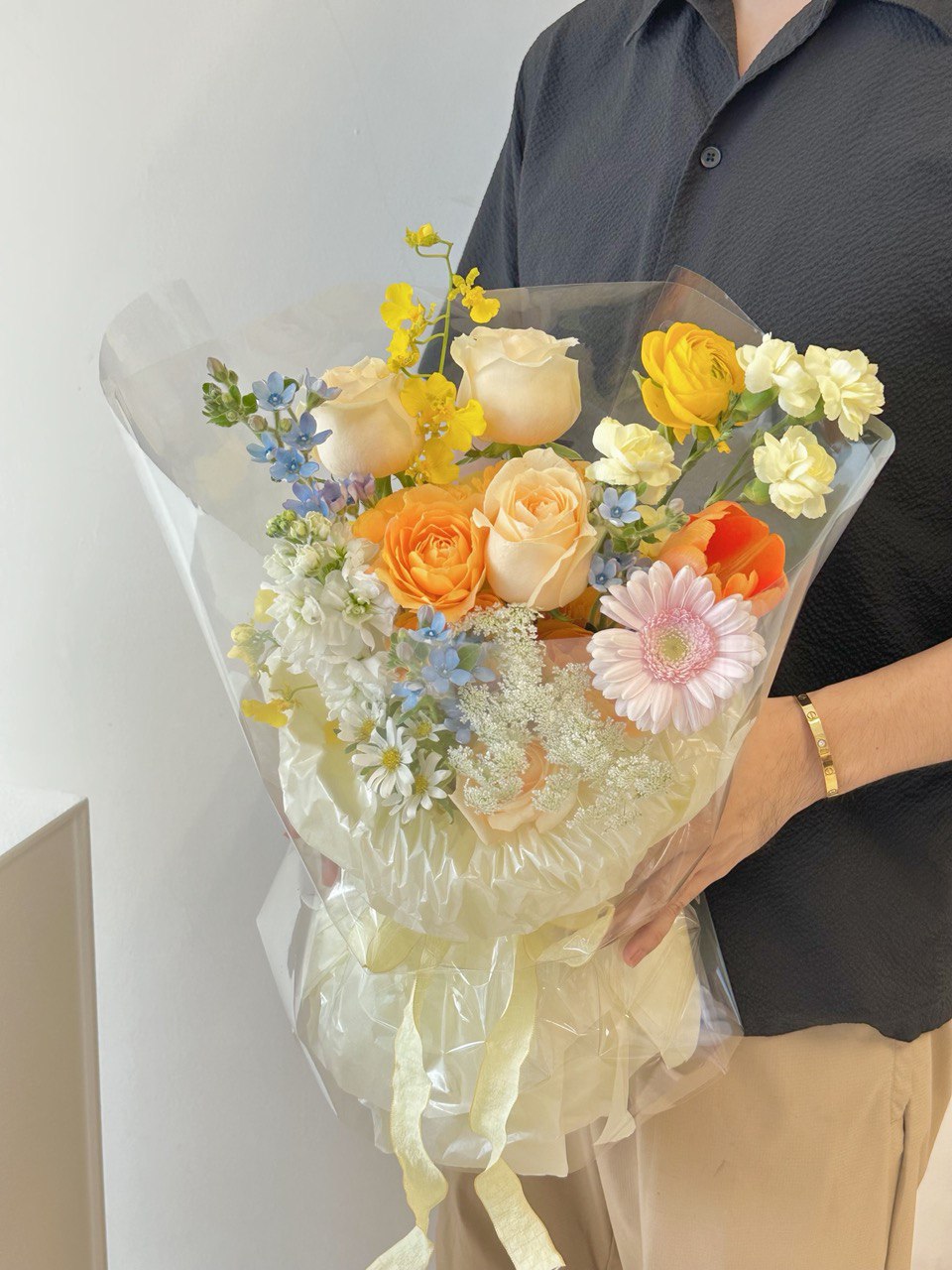 A woman stands in front of a mirror in Subang Jaya, holding a bright bouquet of mixed Korean flowers with a joyful expression.