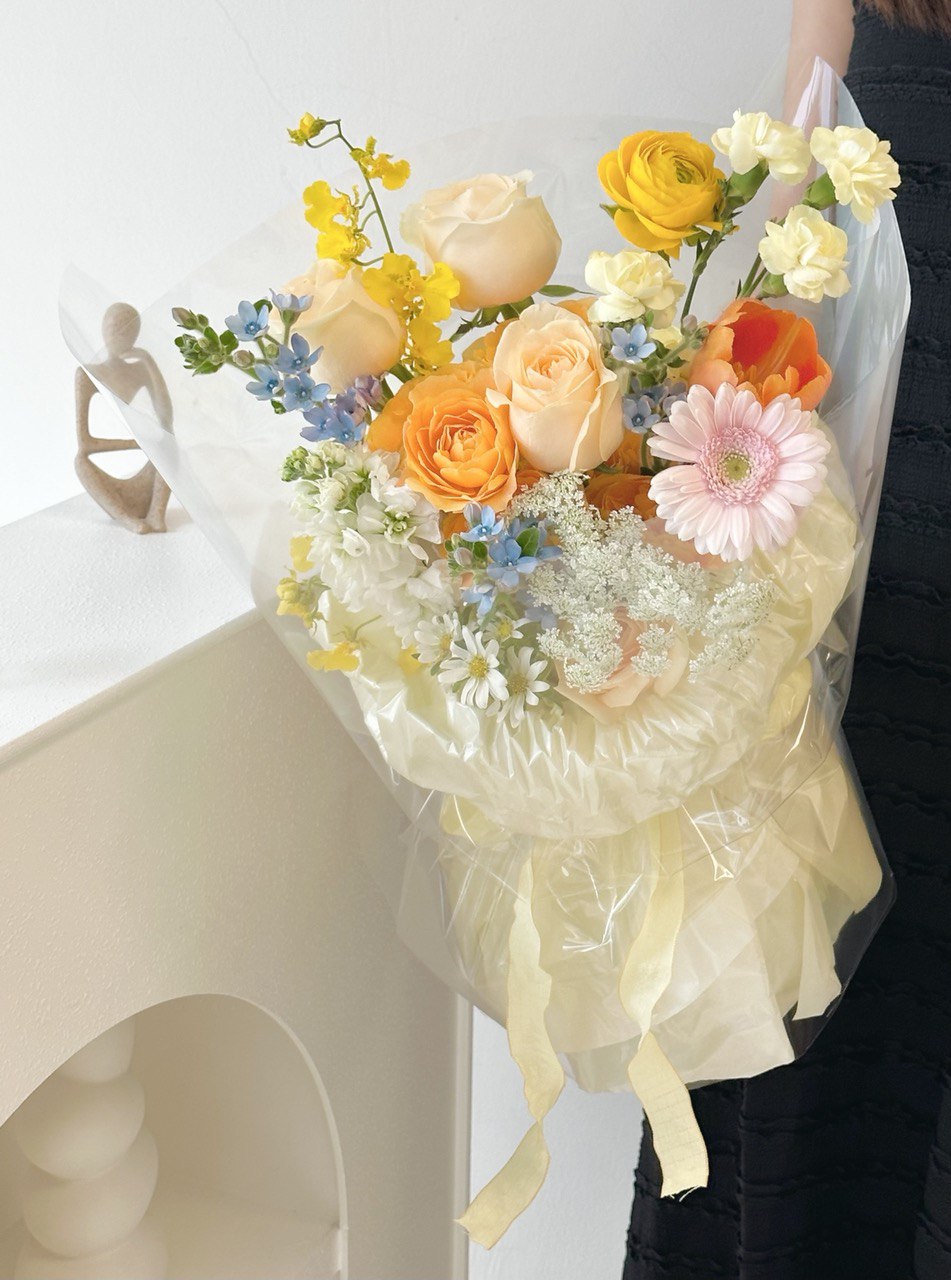 A woman in Subang Jaya holds a colorful bouquet of mixed Korean flowers in front of a mirror, smiling gently.