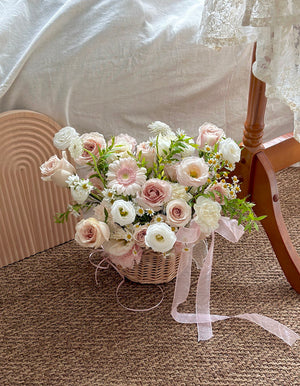 Bouquet of flowers basket in a wicker basket with a white ribbon on a textured surface.