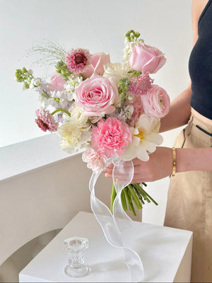 A bride in Kuala Lumpur holds a light pink and white bouquet on her wedding day, showcasing her floral arrangement.