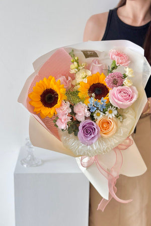 woman in a black gown holds a graduation bouquet of flowers at her graduation day.