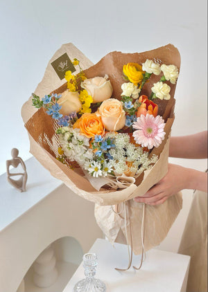 At her birthday event, a woman in a black crop top holds a beautiful, colorful bouquet of flowers.