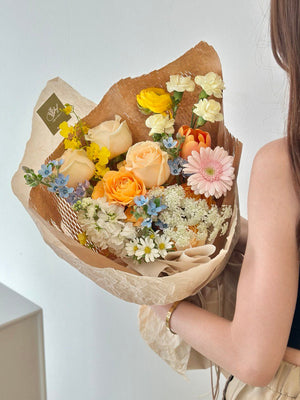 A woman in a black crop top holds a vibrant bouquet of flowers at her birthday celebration.