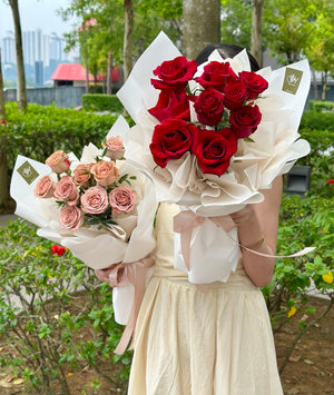 A girl wearing a dress is holding 1 bouquet of cappuccino rose and 1 bouquet of red rose for her Valentines.