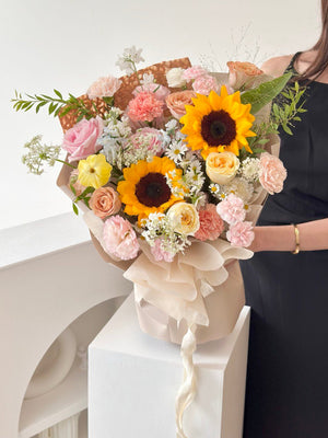 Cheerful graduation bouquet with sunflowers, pink carnations, and soft fillers, designed for university students.