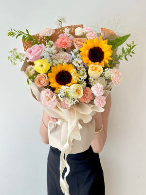 Vibrant sunflower bouquet mixed with pastel roses and carnations, ideal gift for a proud university graduate."