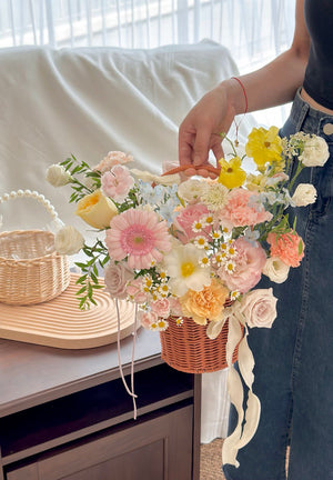 Elegant floral arrangement in a woven basket, ideal for business openings, filled with soft yellow, pink, and white blooms.