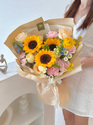 A bouquet of sunflower is holding by a girl dressing in white a white dress marking her graduation from university.