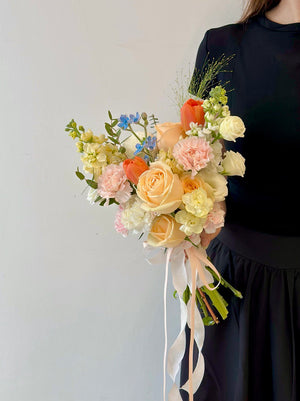 A bride in a black wedding dress proudly displays a vibrant bouquet of flowers on her wedding day.