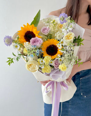 Person holding a bouquet of sunflowers and lace flowers with a white background