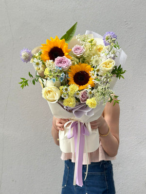 Graduation bouquet featuring cheerful sunflowers, creamy roses, and light lilac tones, symbolizing success and new beginnings.