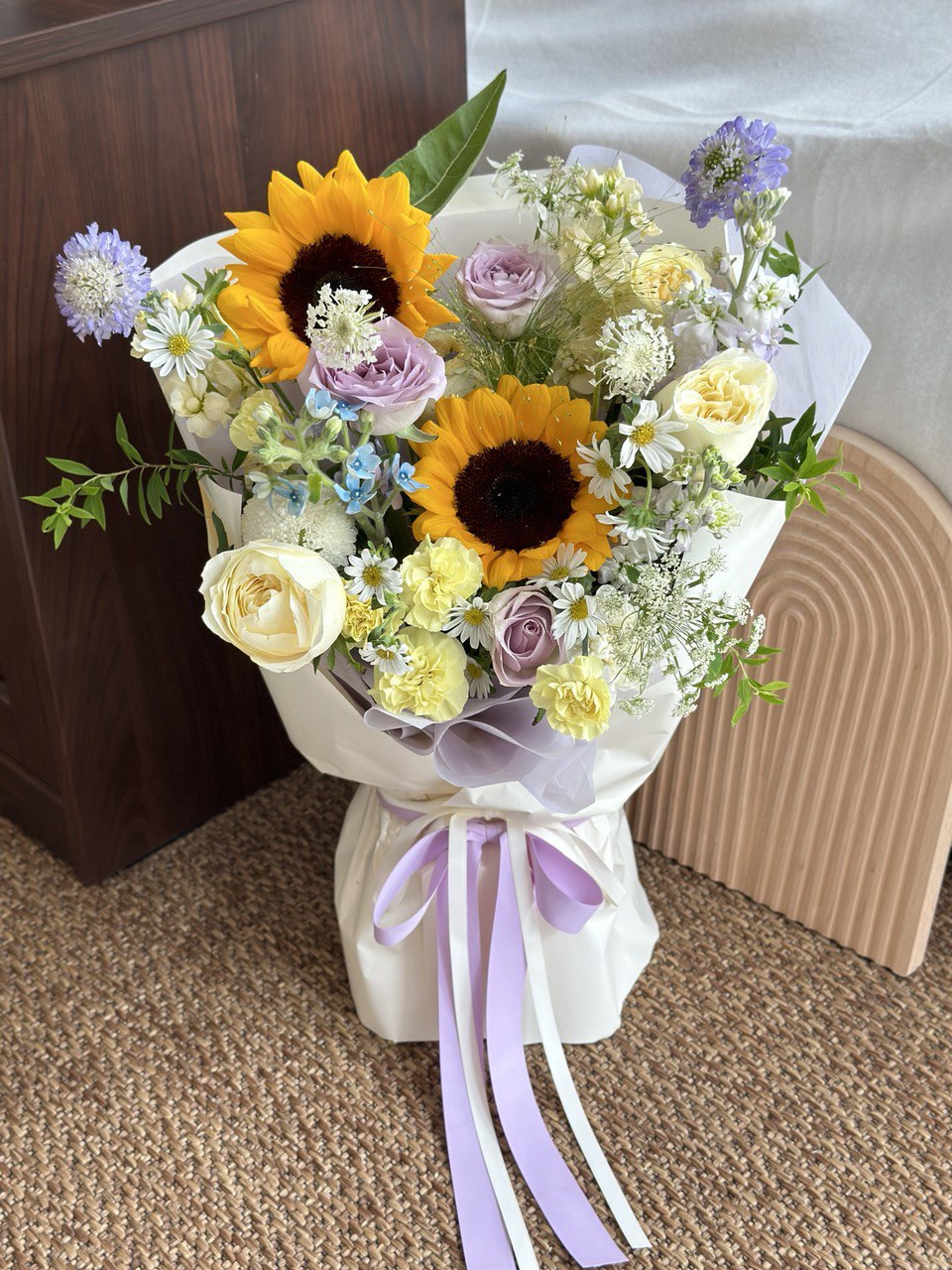 Bright sunflowers paired with pastel roses and delicate fillers, beautifully wrapped with lavender ribbon – ideal for university graduation gifts.