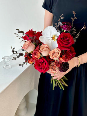 A woman in a black dress holds a bouquet of ROM red roses, preparing for her wedding at Thian Hou Temple.