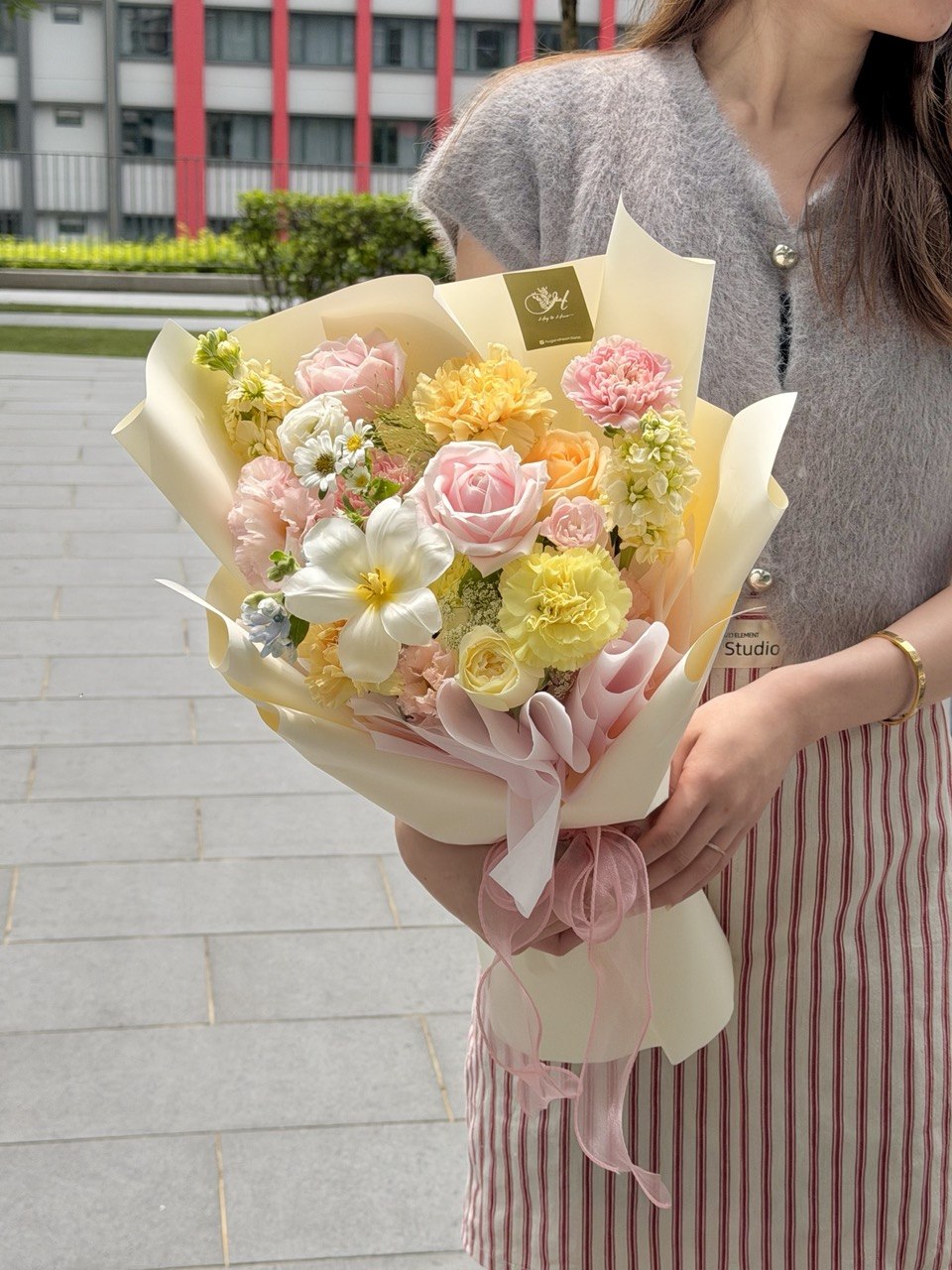 Fresh pink roses and white tulip handcrafted flower bouquet wrapped in yellow wrapper.