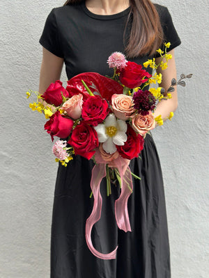 A woman in a black dress holds a wedding bouquet of red and yellow flowers at Thian Hou Temple, Malaysia.
