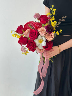A woman in a black long dress holds a bouquet of red and yellow flowers, celebrating her wedding day at Thian Hou Temple, Malaysia.