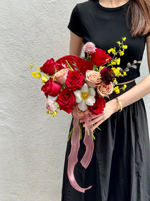 A bride in a black long dress holds a vibrant bouquet of red and yellow flowers at Thian Hou Temple in Malaysia.