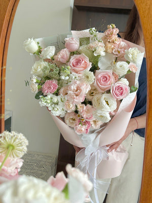 Bouquet of pink and white flowers held by a person in front of a mirror.