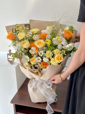 Bouquet of flowers being held by a person on a wooden table with a white background