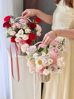 A girl is holding 2 baskets for Mother’s Day flower basket with pink carnations, red roses and white daisies, elegant pastel floral gift Kuala Lumpur same day flower delivery.