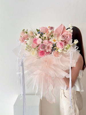 A woman holds a large bouquet of colorful flowers, suitable for anniversaries, birthdays, and proposals.