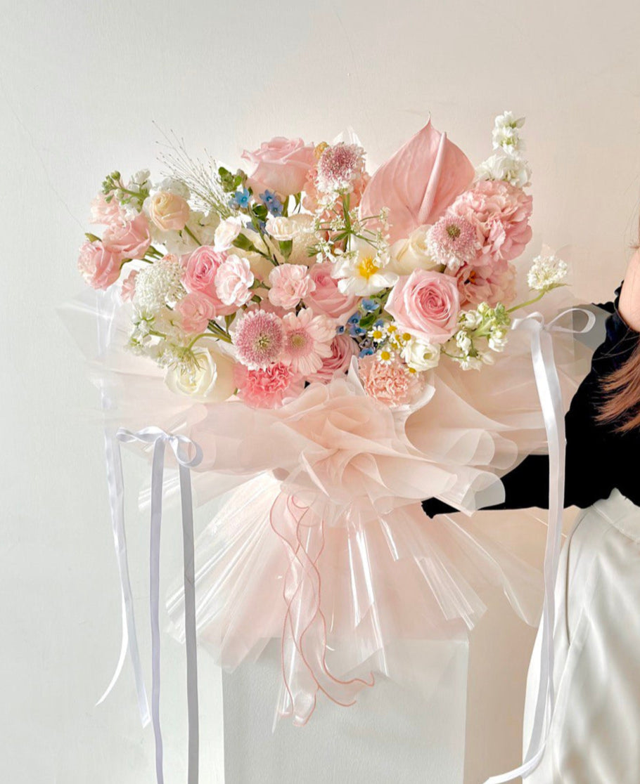 A woman presents a large bouquet of vibrant flowers, ideal for celebrations like anniversaries, birthdays, and proposals.