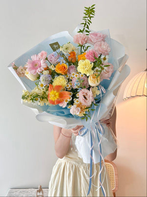 Bouquet of colorful flowers held by a person against a neutral background, perfect for anniversary or birthday flower gift.