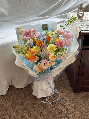 Bouquet of flowers on a small table with a white chair in the background.