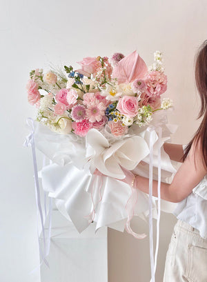 A woman in white attire holds a vibrant bouquet of pink roses, posing for a photoshoot in Subang Jaya.