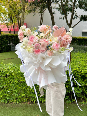 A woman wearing a white top and long jeans poses with a large bouquet of pink roses for a photoshoot in Subang Jaya.