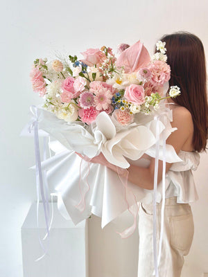 A woman in a white top and jeans holds a large bouquet of pink roses during a photoshoot in Subang Jaya.