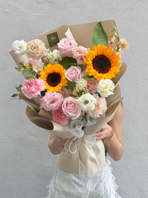 A girl is holding a bouquet of sunflower mixed with pink rose at Sunway geo.