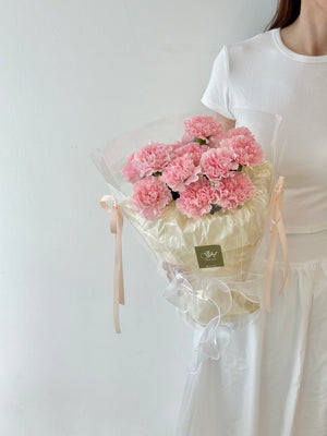 A woman holds a bouquet of pink carnations, a heartfelt gift for her mother on Mother's Day 2025.