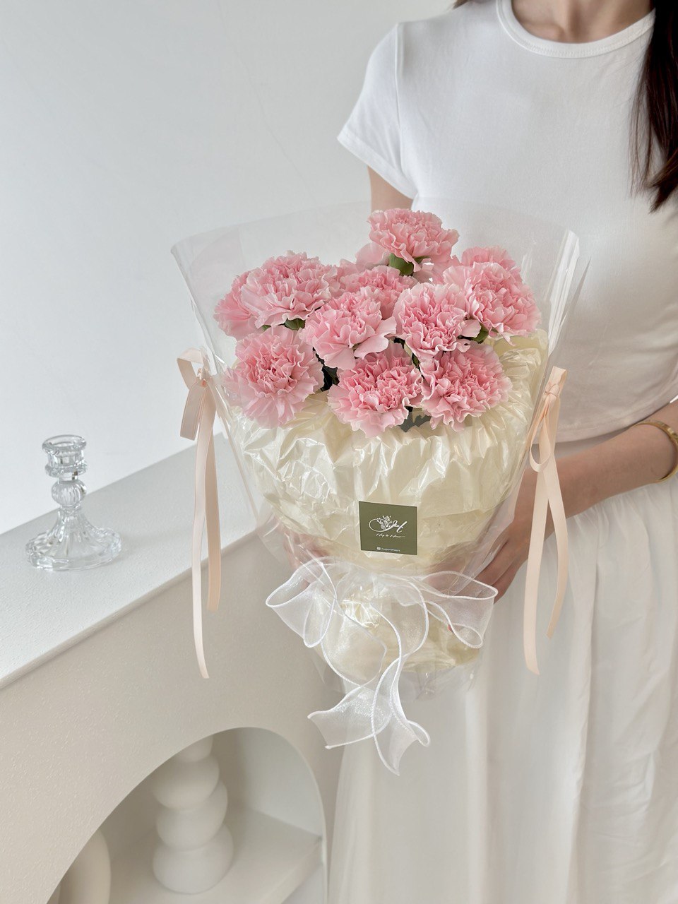 A woman presents a bouquet of pink carnations, celebrating Mother's Day 2025 with a special gift for her mother.