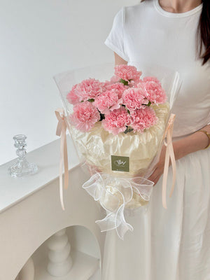 A woman presents a bouquet of pink carnations, celebrating Mother's Day 2025 with a special gift for her mother.
