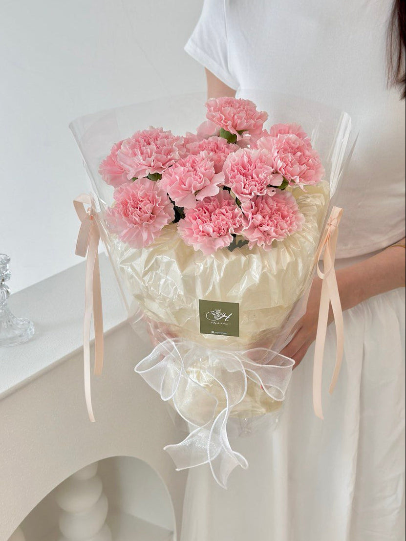 A woman presents a bouquet of pink carnations, celebrating Mother's Day 2025 with a special gift for her mother.