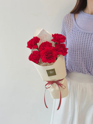 A girl is holding a red carnation bouquet for her mother during mother's day 2025
