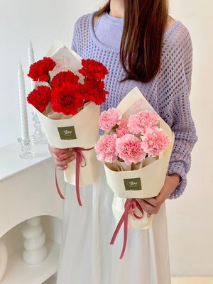 A girl in a purple cardigan holds two bouquets of carnations, celebrating Mother's Day 2025.