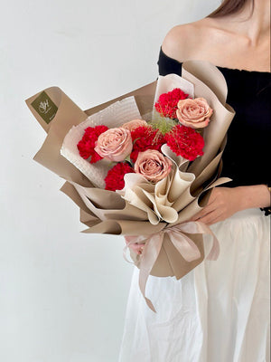 A woman holds a bouquet of red carnations and cappuccino roses, preparing to gift it for Mother's Day in Subang Jaya.