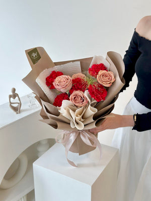 A woman in Subang Jaya holds a Mother's Day bouquet of red carnations and cappuccino roses, ready to gift to her mother.