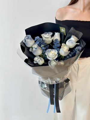 n her Kuala Lumpur room, a woman holds a bouquet of white roses, radiating happiness and elegance.