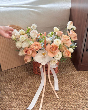 Elegant cappuccino roses arranged in a wicker basket with soft white blooms and long ribbon accents, ideal for get well soon wishes.